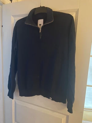 Marinblå half zip tröja från Junkyard  - Svart långärmad tröja från Junkyard i storlek XS men passar bättre på S. Tröjan har en hög krage och en snygg half zip-dragkedja framtill. Stilren och enkel design utan mönster, perfekt för dig som gillar cleana plagg. Materialet känns mjukt och passar bra till kyligare dagar.