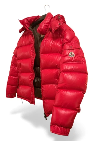 Röd Moncler Maya - Säljer en fet röd pufferjacka från Moncler med ikonisk logga på ärmen. Jackan har en stor huva, dragkedja framtill och två sidofickor med zip. Den är tillverkad i blankt syntetmaterial och har en schysst, quiltad look som verkligen sticker ut. Storlek 4, motsvarar L