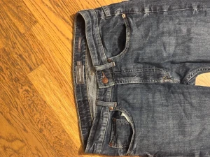 2 par Blå jeansbyxor från Dressmann - Säljer 2 par klassiska blå jeansbyxor från Dressmann med fem fickor, knapp och dragkedja framtill. Jeansen har en rak passform och normal midja, tillverkade i slitstarkt denimtyg. Perfekt för dig som gillar enkel och tidlös stil. 