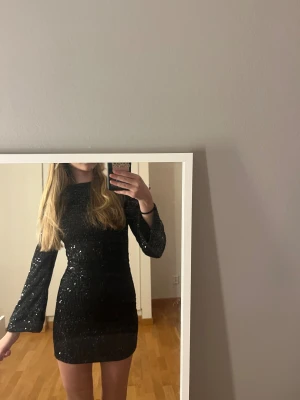 Svart glittrig kortklänning - Supersnygg svart kortklänning med långa ärmar. Knappt använd 
