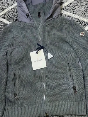 Moncler stickad jacka med dunpanel  Helt ny - Säljer en helt ny Moncler-jacka i storlek L, aldrig använd, lappar kvar. En riktigt snygg och exklusiv modell som kombinerar stickad kvalitet med vadderad dunpanel för både stil och värme.