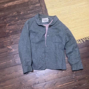 Grå overshirt från Atelier - Säljer en stilren grå overshirt från Atelier. Jackan har två bröstfickor, knäppning framtill och en rak, lite boxig passform. Perfekt att slänga över en hoodie eller t-shirt för en chill look.