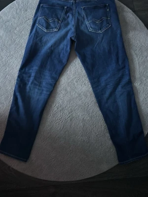 Blå jeans med raka ben - Snygga blå jeans med klassisk femficksdesign och raka ben. Jeansen har kontrastsömmar och diskret tvättad look, vilket ger dem en cool vibe. Materialet är slitstarkt jeans och passformen är normal. Perfekt för dig som gillar enkel och stilren denim.