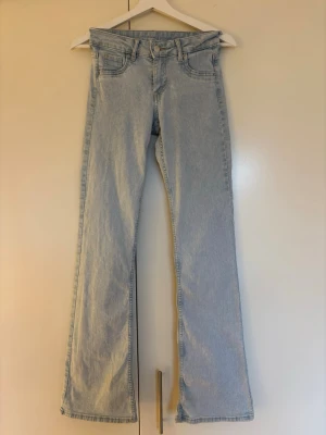 Bootcut ljusblå jeans med fem fickor från HM storlek 34 - Säljer ett par ljusblå bootcut jeans med låg midja med klassisk femficksdesign. Jeansen är från HM i storlek 34