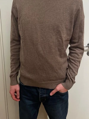 Brun stickad tröja från Springfield - Snygg brun stickad tröja från Springfield i storlek S. Tröjan har rund hals, långa ärmar och ribbade muddar vid ärmslut och nederkant. Materialet är 64% bomull och 36% linne, vilket gör den mjuk och skön. Perfekt för dig som gillar enkel och stilren design.