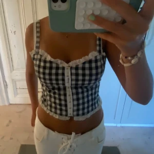 Rutig topp med spetsdetaljer - Supersöt korsettopp med svartvitt rutigt mönster och spetskanter! Använd endast 2 gånger!💕 Storleken är xs men materialet ör otroligt stretchigt så passar S också! Pris kan diskuteras o skriv för fler bilder