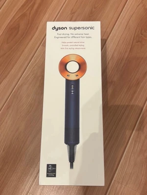 Dyson Supersonic hårfön - Dyson Supersonic hårtork i mörkgrå och kopparfärg med fem stylingtillbehör. Modern design med rund öppning och magnetiska munstycken. Perfekt för att skapa olika hårstilar och skydda hårets glans. Levereras i originalförpackning med alla tillbehör.