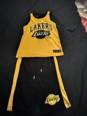 Ett Lakers kitt med James på ruggen - Bilderna visar ett Los Angeles Lakers basketset med tröja och shorts, gul och svart med tryck och autograf.