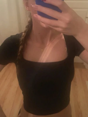 Svart croppad topp från Amisu - Säljer en svart croppad topp från Amisu med fyrkantig urringning och korta ärmar. Toppen har en tight passform och är tillverkad i ett mjukt, stretchigt material som sitter snyggt på kroppen. Perfekt till jeans, träningskläder eller kjol för en clean look.