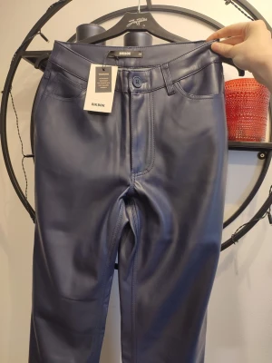 PU Byxor i storlek 34 - Snygga mörkblå PU-byxor i storlek 34. Sköna och mjuka på insidan. Ord.pris 599kr. Helt nya med prislapp kvar.