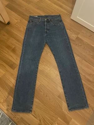 Levi's 501 blå  - Levis 501 i storlek W.28 L.32. Har ett litet hål längst ner på ena benet men inget man tänker på, kan skicka närmare bild på de