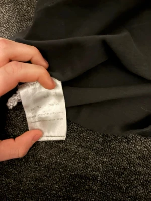 Svart Moncler t-shirt med patch - Svart t-shirt från Moncler i bomull med klassisk v-ringning och korta ärmar. På bröstet sitter en snygg broderad Moncler-patch som ger en exklusiv vibe. Perfekt för dig som gillar stilrena och ikoniska plagg med en twist. finns även kvitto 