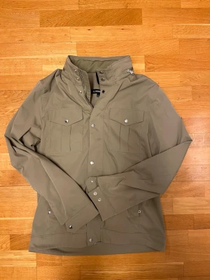 J.lindeberg field jacket bailey aloe green - Säljer en snygg field jacket från j.lindeberg i modellen bailey. Storleken är L men passar mig bra som brukar ha M. Färgen heter aloe green men är olivgrön. Skriv gärna ifall ni undrar något!