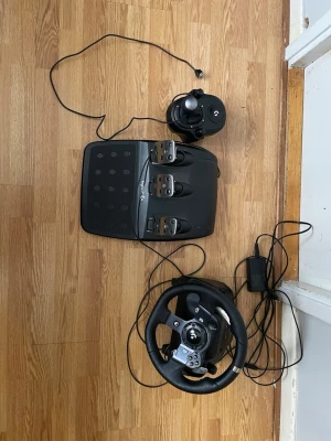 Logitech G920 Driving Force Racing Wheel & Pedals - Komplett Logitech G920 racerratt med pedaler och växelspak. Perfekt för realistisk racingupplevelse på PC och Xbox. Ratten har slitstarkt läder, pedaler i metall och separat växelspak. Allt ser ut att vara i gott skick utan synliga defekter. Ända felet är att man kommer behöva en trä kloss för att kunna sätta fast ratten i bänken då en har trillat bort. 