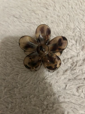 Brun leopardmönstrad hårklämma st pris - Säljer en brun hårklämma i form av en blomma med leopardmönster. Och en annan som är leopardmönstrad som ser ut som en fjäril. Klämmorna är gjord i plast och har en snygg glansig finish. Perfekt för att sätta upp håret på ett trendigt sätt. Passar dig som gillar djurmönster och vill ha en cool detalj i håret. ALDRIG ANVÄNTS