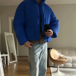 Blå pufferjacka från Zara - Säljer en blå pufferjacka från Zara i storlek M. Jackan har en hög krage, två stora fickor framtill  jackan har en loose passform köptes förra vintern 