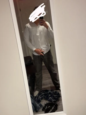 Vit skjorta från POSHAWN, storlek 40/S - Säljer en stilren vit skjorta från POSHAWN i storlek 40 passar S. Skjortan har klassisk krage, lång ärm och knappar framtill. Materialet har en diskret struktur som ger en snygg touch. Perfekt för dig som gillar clean och enkel stil.