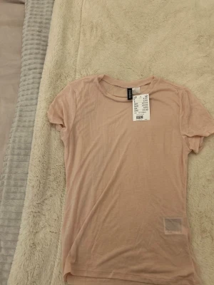 Ljusrosa genomginlig t-shirt från HM💕 - Säljer en jättefin ljusrosa lite genomskinlig T-shirt från HM. Funkar både till vardags och fest. Dessutom helt oanvänd och i toppen skick!!💕
