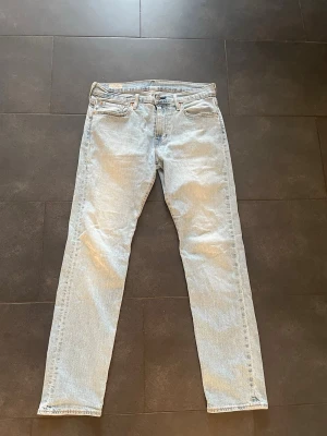 Levi's Premium ljusblå jeans 501 - Ljusblå Levi's Premium 501 jeans med klassisk femficksdesign och raka ben. Jeansen har en snygg vintage-wash och är tillverkade i slitstarkt bomullsmaterial. Passformen är straight och de har knappgylf samt detaljer med nitar. Perfekt för dig som gillar tidlös denimstil.