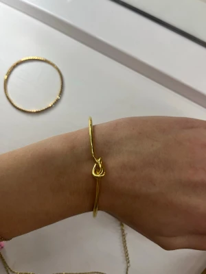 Guldfärgad armbandsbåge med knut - Snygg och stilren guldfärgad armbandsbåge med en cool knutdetalj framtill. Armbandet är öppet i ändarna och är jättefin💛 det är rostfritt stål och helt oanvänt. 