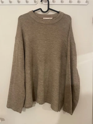 Beige stickad tröja från 157 - Säljer en beige stickad tröja från 157 i storlek M. Tröjan har en rundad halsringning, ribbade muddar och en loose passform med långa ärmar. Perfekt för kyliga dagar och enkel att matcha med jeans eller kjol.