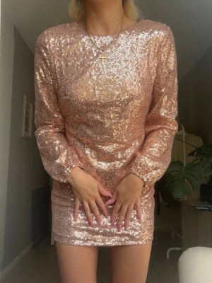 Glittrig rosa paljettklänning - Säljer en superfin kort klänning i rosa av glittriga paljetter. Klänningen har lång ärm och en tight passform. Aldrig använd så super fint skick 