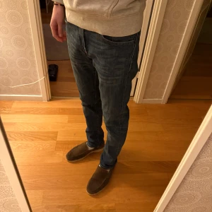 Levi's 511 blå jeans slim fit - Säljer ett par Levi's 511 jeans i klassisk blå tvätt med slim fit och raka ben. Jeansen har fem fickor, snygga kontrastsömmar och den ikoniska Levi's-lappen bak. Perfekt passform för dig som gillar en modern och stilren look.