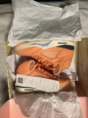 Nike Air Jordan 5 x Kith Peach - Nike Air Jordan 5 x Kith sneakers i en unik persikofärgad och ljusblå färgway. Skorna har quiltad satin på insidan, detaljerad snörning och en platt sula med synlig Nike-logga och Jumpman under sulan. Ovandelen är i skinn med meshpaneler och coola blå detaljer på sidan.pris kan diskuteras 