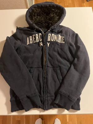 Abercrombie & fitch päls fodrad hoodiejacka wolf jaw jacket - Abercrombie & fitch päls fodrad hoodiejacka wolf jaw jacket i storlek L grå/mörkblå förg. Otroligt fet med slitningar vid dragkedjan och längst ner vilket gör den ännu fetare vintage look. Väldigt sällsynt och i bra skick. Pris 850 kr kolla gärna in mina andra annonser för rabatt och mer feta kläder😃