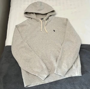 Grå Ralph Lauren Hoodie  - Riktigt snygg grå Ralph Lauren Hoodie. Storlek L, kan säkert också passa en större M. Inte använd mycket och i fint skick. Perfekt för vintern☃️och kanske en bra julklapp också🙌🏻