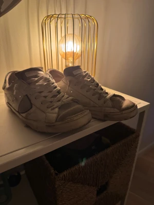 Philippe model - Säljer ett par vita Philippe Model sneakers med klassisk snörning och rund tå. Skorna har svarta detaljer på sidan och tåpartiet, samt en platt sula i svart gummi. Materialet är skinn med inslag av mocka. Perfekt för dig som gillar en clean och urban stil. Dessa pärlor är väl använda så ha det i åtanke då de finns bild på de i annonsen, dessa är äkta då dem är köpta direkt från Philippe models hemsida, online kvitto och dust bag medföljer😄