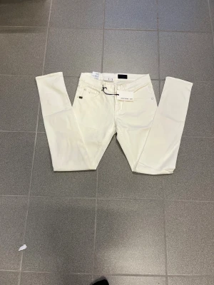 Vita slimmade jeans från Tiger of sweden W29 L32 - Snygga vita jeans från T/J i storlek W29 L32. klassisk femficksdesign och bälteshällor. Perfekt för dig som gillar en slim och modern look. Materialet är mjukt och stretchigt för extra komfort. Nya 