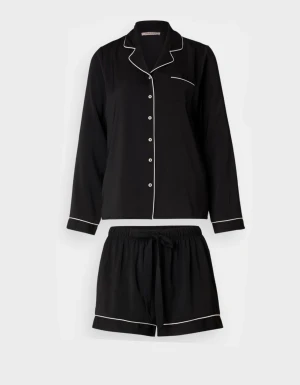 Svart pyjamas med vit kant - Svarta pyjamasshorts med vit piping och avslappnad passform. Shortsen har elastisk midja med snörning och är tillverkade i ett mjukt, vävt material. Klassisk look med raka ben och diskreta detaljer som ger en stilren vibe. Tröjan har vita knappar och vita kanter.
