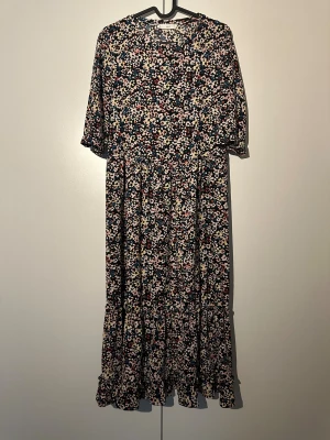 Mango blommig klänning, storlek M - Långärmad klänning med ett blommigt mönster i olika färger. Klänningen har en avslappnad passform och en volang nedtill.