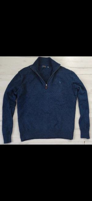 Blå stickad tröja Polo Ralph Lauren - Snygg marinblå stickad tröja från Polo Ralph Lauren i storlek XXL. Tröjan har en ribbad krage med half zip-dragkedja och långa ärmar. Perfekt för dig som gillar klassisk stil med en modern touch. 