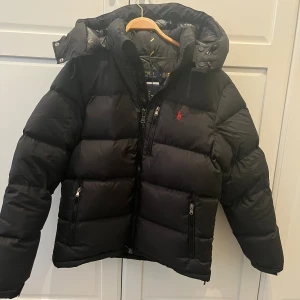 Svart pufferjacka från Polo Ralph Lauren - Säljer denna stilrena Ralph Lauren jackan, då den inte längre passar. Modellen är ”The Gorham Down Jacket”. Strlk M. Jackan är i perfekt kondition utan några synliga tecken på användning. 🌟 Priset är inte hugget i sten 🌟 och kan sänkas vid diskussion. Hör gärna av dig om du har några frågor
