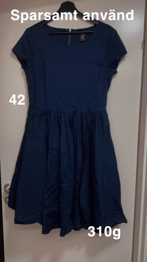 Mörkblå kort klänning med rund hals - Enkel och snygg mörkblå klänning från ellos med kort ärm och rund halsringning. Kjolen är utställd och klänningen har dragkedja i ryggen. Perfekt för dig som gillar stilrena plagg med en klassisk siluett.🌸 Sparsamt använd. Storlek 42