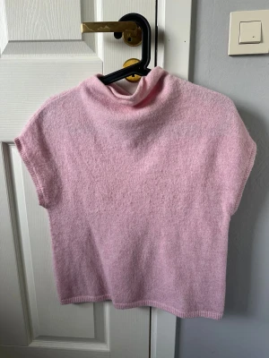 Ljusrosa polotopp från Lindex - Supermysig ljusrosa polotopp från Lindex i mjukt stickat material. Toppen har en hög krage och är ärmlös. Endast använd 1 gång och därav i bra skick🩷