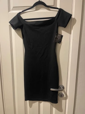 Svart offshoulder klänning Nelly  - Snygg svart kortklänning från Nelly. Modellen är offshoulder med smal passform. Klänningen är aldrig använd och lapparna sitter kvar. 