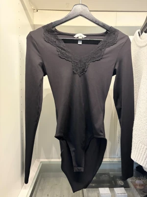 Svart långärmad body med spets - Svart body från H&M med lång ärm och snygg v-ringad halsringning dekorerad med spets. Modellen är tight och sitter figurnära. Inspirerad av intimissimis tröjor. Aldrig använt, mycket bra skick. 