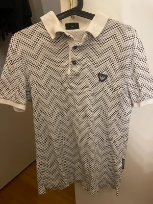 Piké - Vit piké med mönster från Emporio Armani. Herr. Storlek M. Qr koden leder till Armani webbplatsen.