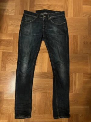 Mörkblå Dondup jeans George strl 31 - Hallö! Jovlarns härliga mörkblå George från Dondup i storlek 31. Klassisk femficksmodell med orangea sömmar och diskret tvättad look. Jeansen har smal passform och är tillverkade i slitstarkt denimtyg med bekväm stretch. Liten lagning i skrevet men inget som märks!.