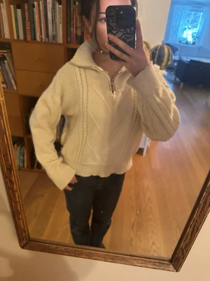 Vit stickad tröja med half zip - Mysig vit stickad tröja med hög krage och half zip-dragkedja. Snygga stickade detaljer och breda muddar vid ärmslut och nederkant. Perfekt för lager-på-lager och chill dagar.