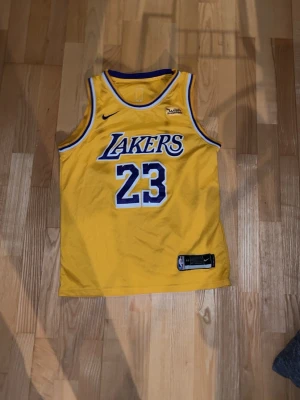 Lakers linne - Gult Los Angeles Lakers-linne med nummer 23. Ärmlös design i lätt material med klassiska detaljer och officiella NBA/Nike-logotyper.