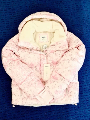 Hollister blommig rosa pufferjacka - Köpte den ett tag sedan och har aldrig använt. Jackan har två fickor på utsidan och en på insidan. Luvan går att ta av. Den är jätte gosig, varm & mjuk + vatten/vind avvisande. Storlek S 💞