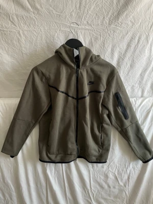 Nike teck fleece set - Snyggt och stilrent Nike Tech Fleece-set i khaki/olivgrön färg. Setet består av zip-hoodie och matchande byxor med klassiska Tech-detaljer.