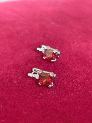 Röd dunväst med silverdetaljer 925 S - Snygg dunväst i röd färg med glittrande silverdetaljer. 925 S Västen har en fyrkantig form och är tillverkad i syntetmaterial med quiltad design. Perfekt för dig som vill sticka ut med en färgstark look.