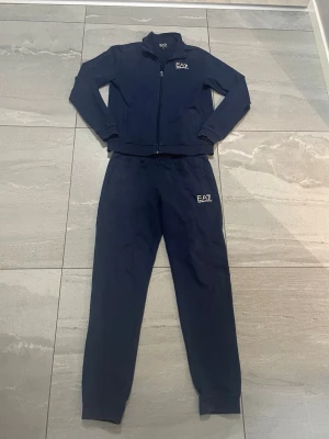 Marinblå mjukisbyxor EA7 Emporio Armani - Säljer ett par marinblå mjukisbyxor från EA7 Emporio Armani. Byxorna har en relaxed passform med resår i benslut och midja, samt EA7-logga tryckt på benet. Tillverkade i mjukt bomullsmaterial som är perfekt för chill eller träning.