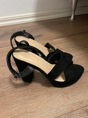 Svarta pumps med klacktå och platå - Snygga svarta sandaler med bred klack och platåsula. Skorna har korsade remmar framtill, öppen tå och justerbar rem runt hälen. Tillverkade i mockaliknande material som ger en lyxig känsla. Endast prövad. 🌷| pris kan diskuteras