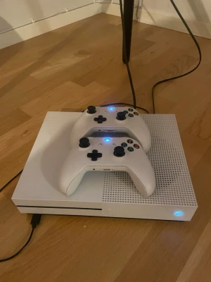 Xbox One med två trådlösa handkontroller - Snygg Xbox One  i vitt med två trådlösa handkontroller. Konsolen är i gott skick med endast mindre ytliga märken. Perfekt för spelkvällar med vänner eller familj. Allt fungerar som det ska och båda kontrollerna är anslutna och redo att användas. Forza 4 med följer . 